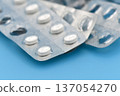 White pills in foil blister packs are placed on a blue background. 137054270