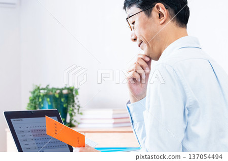 A middle-aged man thinking while looking at his pension book A middle-aged man thinking while looking at his pension book 137054494