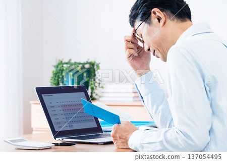 一位中年男子一邊看著他的退休金手冊一邊思考。 137054495