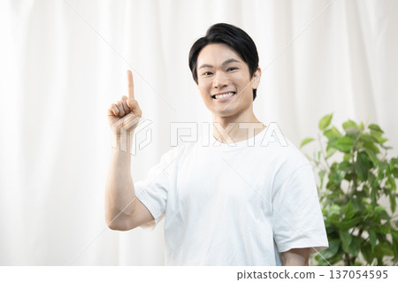 Smiling man pointing up his index finger 137054595