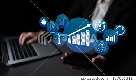 Businessman Holding Smartphone with Financial Growth Icons and Charts on Dark Background Representing Digital Economy and Investment Trends Quark Businessman Holding Smartphone with Financial Growth Icons and Charts on Dark Background Representing Digital Economy and Investment Trends Quark 137055311