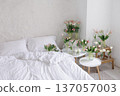 Bright bedroom interior with multiple tulip bouquets in glass vases near bed. Soft natural light, fresh spring flowers creating cozy home atmosphere. 137057003