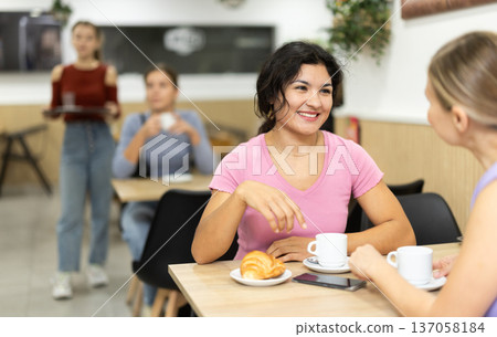 In cafe, Latin girl chatting sweetly during tea party with girl buddy In cafe, Latin girl chatting sweetly during tea party with girl buddy 137058184