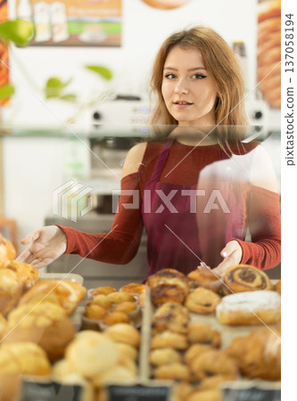 Young female waitress offers fresh pastries Young female waitress offers fresh pastries 137058194