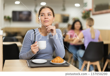 Young girl enjoying coffee and croissant in cafeteria Young girl enjoying coffee and croissant in cafeteria 137058200
