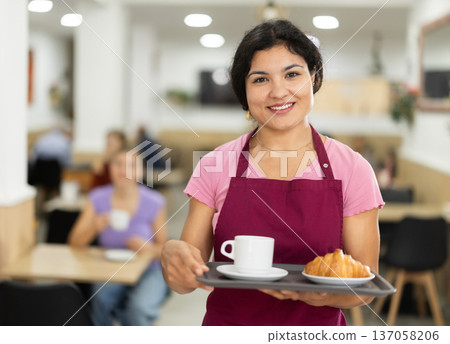 Positive female waitress carries coffee and croissants on tray 137058206