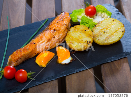 Deliciously steak of fried salmon with potatoes and egg yolk on plate 137058276