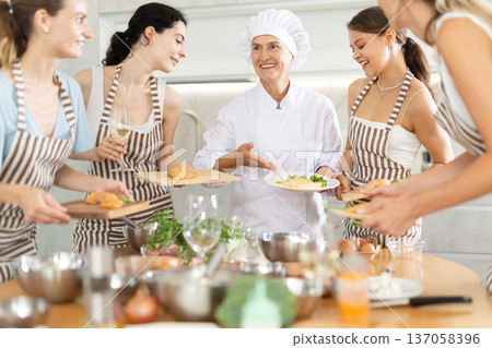 Mature female cook holding plate with cooked chicken 137058396