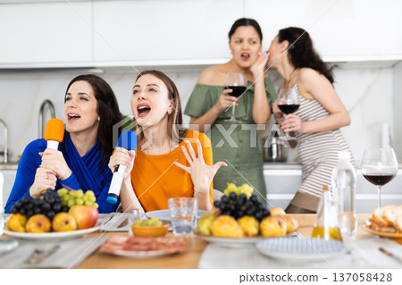 Cheerful female friends singing together at home karaoke Cheerful female friends singing together at home karaoke 137058428