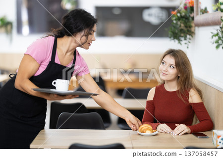 Young female waitress serves order to customer Young female waitress serves order to customer 137058457