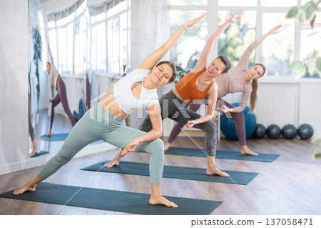 Girl conducts lesson, training for girls in yoga studio and performs lateral elongated angle asana 137058471