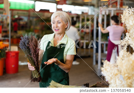 Old saleswoman holding bundles of lavender in open-air plants market 137058540