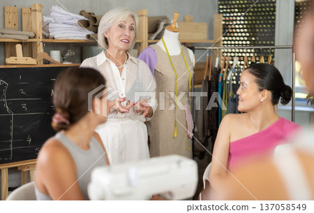 Elderly female teacher conducts master class on sewing Elderly female teacher conducts master class on sewing 137058549