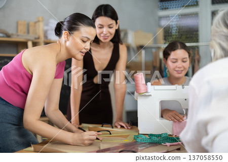 Young female teacher explains to group how to draw pattern Young female teacher explains to group how to draw pattern 137058550