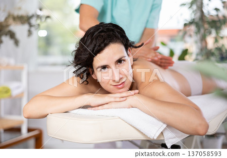 Masseur doing back massage to adult woman 137058593