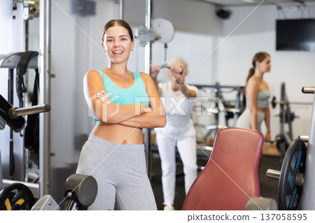 Young girl trainer in sportswear poses in middle of fitness center gym. 137058595