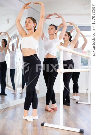 Female ballet dancers doing various ballet movements at ballet barre in fifth position Female ballet dancers doing various ballet movements at ballet barre in fifth position 137058597