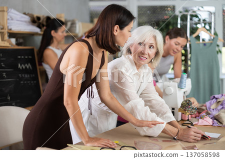Mature woman drawing on paper during dressmaking classes Mature woman drawing on paper during dressmaking classes 137058598