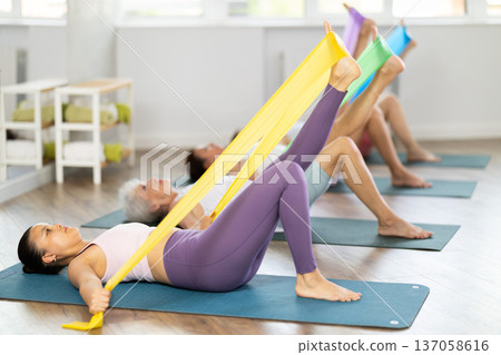 Asian woman exercising with resistance band in group fitness class Asian woman exercising with resistance band in group fitness class 137058616