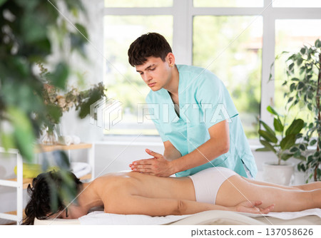 Young guy doing a back massage to adult woman Young guy doing a back massage to adult woman 137058626