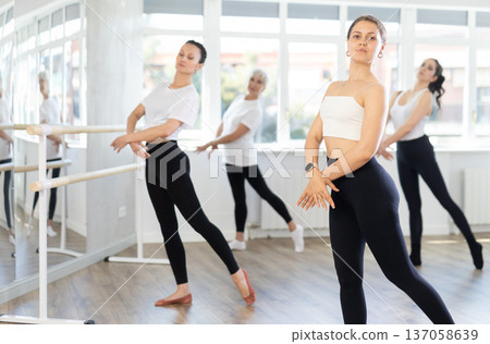 Young woman in group lesson with students rehearses, practices ballet dance, staging. 137058639