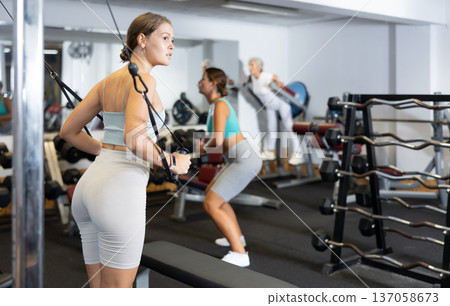Active athlete young woman during exercises on crossover exercise machine with loops and weighting 137058673