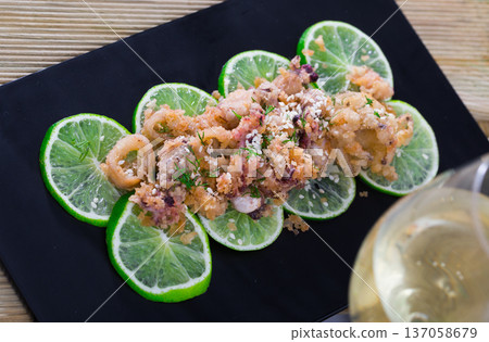Fried calamari with sepia in batter of tempera flour served with glass of wine 137058679