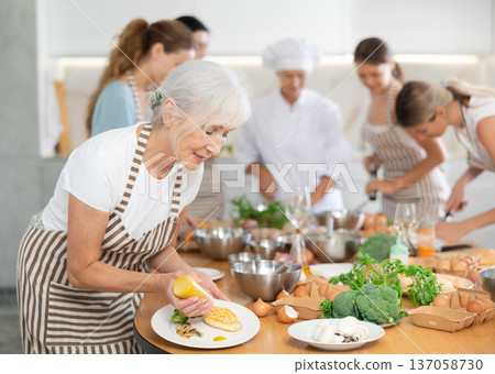 Elderly woman pouring sauce into dish at master class Elderly woman pouring sauce into dish at master class 137058730
