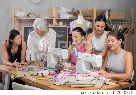 Group of busy women sewing and drawing with teacher at dressmaking courses Group of busy women sewing and drawing with teacher at dressmaking courses 137058731