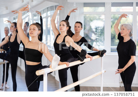 Students of dance studio perform exercises under supervision of mature female coach. 137058751