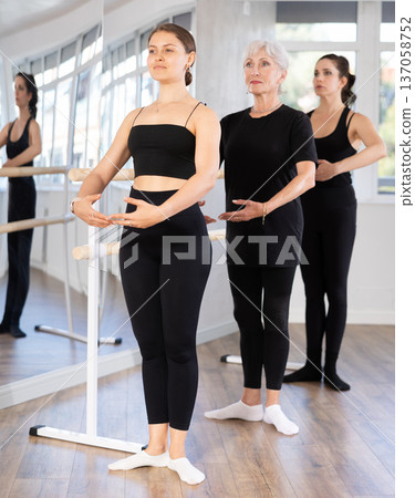 Group of women stand in position at ballet barre Group of women stand in position at ballet barre 137058752