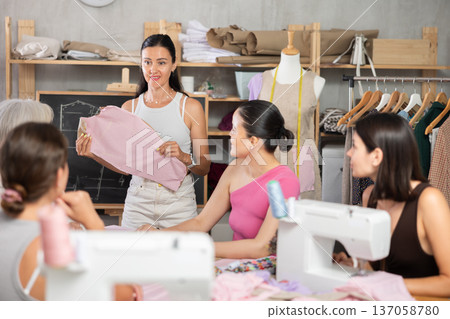 Adult female teacher conducts master class on sewing Adult female teacher conducts master class on sewing 137058780