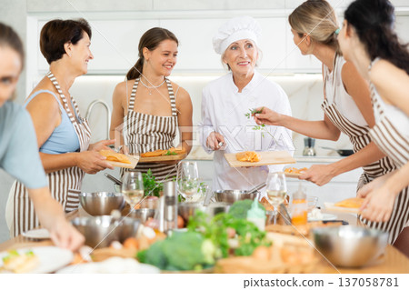 Mature female cook holding cutting board with raw chicken 137058781