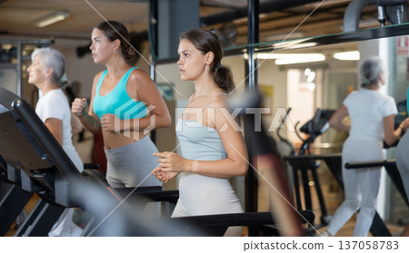 Woman doing cardio workout running on treadmill at fitness center Woman doing cardio workout running on treadmill at fitness center 137058783
