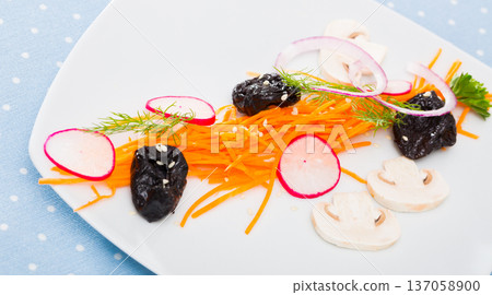 Vegetarian dish, salad from carrot, radishes and prunes served at plate Vegetarian dish, salad from carrot, radishes and prunes served at plate 137058900