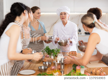 Mature female cook holding bowl and whisk 137058903