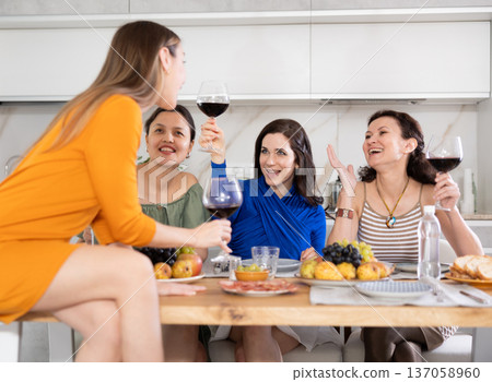 Girlfriends chatting and drinking wine in kitchen 137058960