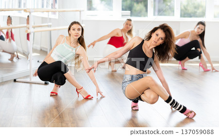 Woman with female perform dance in heels, squat down, actively repeat movements of instructor. 137059088