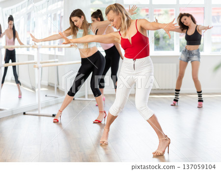 During lesson, woman learn to move and perform dance in heels with women companions 137059104