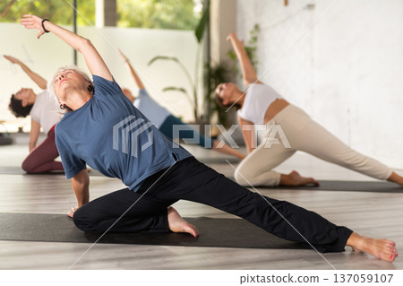 Active senior woman exercising stretching workout and incline during yoga class in fitness studio 137059107