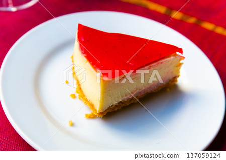 Slice of tender cheesecake with layer of strawberry jelly 137059124