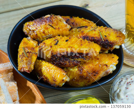Fried chicken wings served in black bowl, two sauses and bread Fried chicken wings served in black bowl, two sauses and bread 137059130