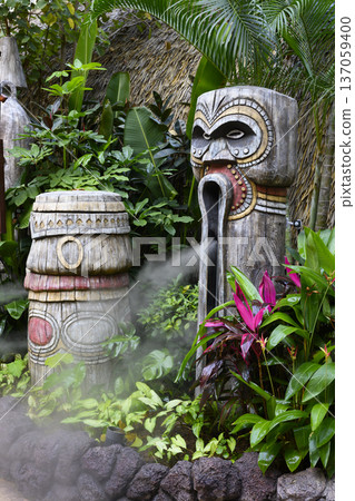 Wooden carved idols emitting steam among tropical flowers in the city park in Sanya, China Wooden carved idols emitting steam among tropical flowers in the city park in Sanya, China 137059400