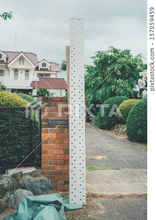 A long aluminum scaffolding board leaned against a wall by a gardener 137059459