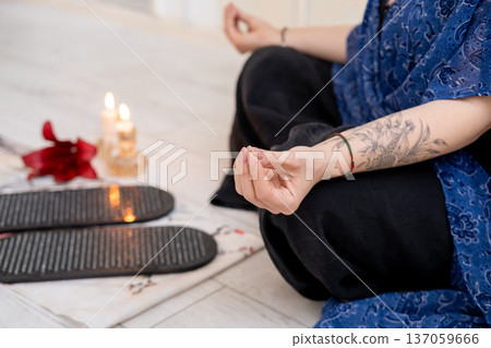 Woman practice yoga. Board sadhu. Sitting in lotus position mudra hands before sharp nails on mat in front of burning fire candles spiritual growth mental health. Woman practice yoga. Board sadhu. Sitting in lotus position mudra hands before sharp nails on mat in front of burning fire candles spiritual growth mental health. 137059666
