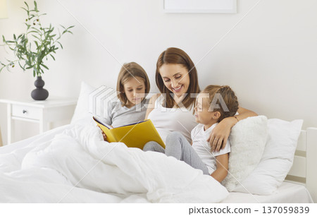 Mother And Children Reading A Book Together In Bed At Home 137059839