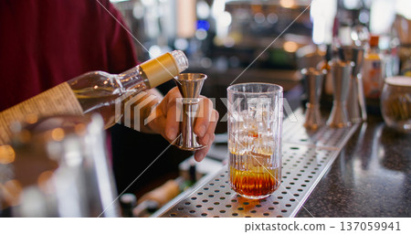 Mixologist work. Making cocktail. Bartender pouring sweet aroma color syrup from metal jigger to glass. Flavored refreshing drink. 137059941