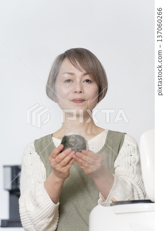 Senior woman making rice balls in the kitchen Senior woman making rice balls in the kitchen 137060266