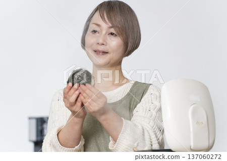 Senior woman making rice balls in the kitchen Senior woman making rice balls in the kitchen 137060272