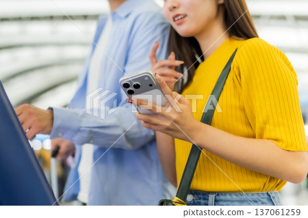 Two people using smartphones at the airport. Photo courtesy of Kansai International Airport (KIX). Two people using smartphones at the airport. Photo courtesy of Kansai International Airport (KIX). 137061259